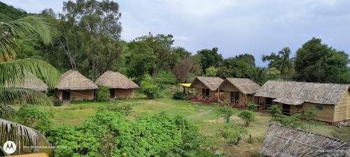 a group of houses with thatched roofs and trees at Banana Tree Home Stay in Hampi