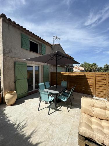un patio avec une table, des chaises et un parasol dans l'établissement La Maison Provencale, à Cogolin
