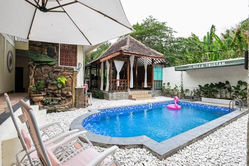 a swimming pool with an umbrella and a gazebo at Villa de Tristan Yogyakarta in Mutihan
