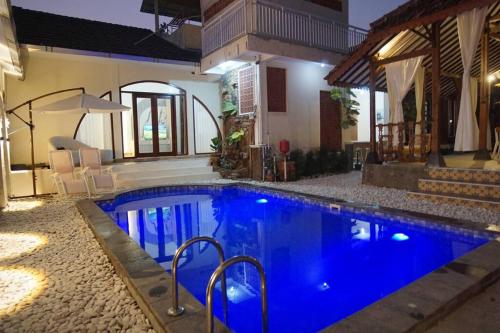 a swimming pool with blue water in front of a house at Villa de Tristan Yogyakarta in Mutihan