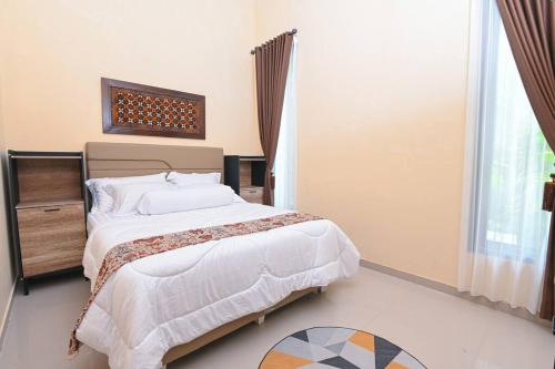 a bedroom with a large bed and a window at Villa de Tristan Yogyakarta in Mutihan