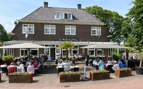 a group of people sitting at tables in front of a building at De Gouden Molen in Rossum