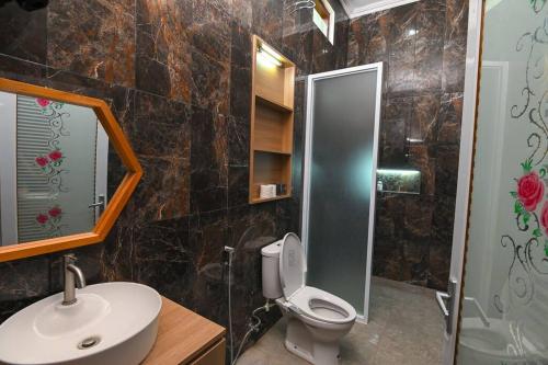 a bathroom with a toilet and a sink and a mirror at Villa de Tristan Yogyakarta in Mutihan