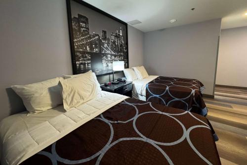 a hotel room with two beds and a picture on the wall at Super 8 by Wyndham Brooklyn Fulton Street Broadway Junction in Brooklyn