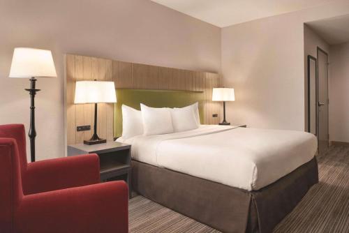 a hotel room with a large bed and a red chair at Country Inn & Suites by Radisson, Eagan, MN in Eagan