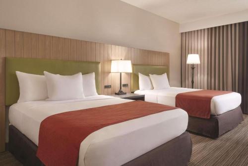a hotel room with two beds and two lamps at Country Inn & Suites by Radisson, Eagan, MN in Eagan
