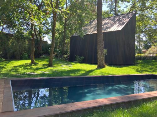 une piscine dans la cour d'une maison dans l'établissement NOUVEAU - Ecolodge 'Calme et Nature' - Avec Piscine au Golf-Lac de Biscarrosse - Couchage 2 personnes, à Biscarrosse