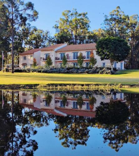 a house on a golf course with a reflection in the water at Villa Provence Estate in Pokolbin