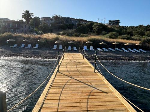 a wooden walkway leading to a beach with chairs at Merlot Assos in Ayvacık