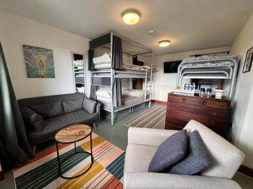 a living room with a couch and a room with bunk beds at Lands End Hostel and B&B in Sennen