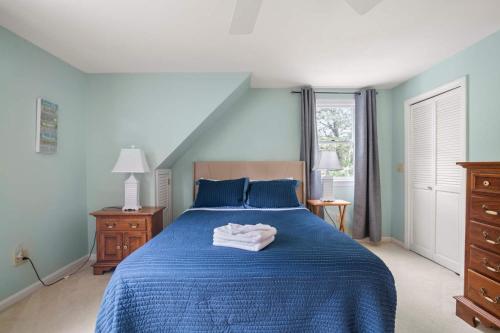 a bedroom with a blue bed with a towel on it at Game Room Walk to Nantucket Sound in Chatham
