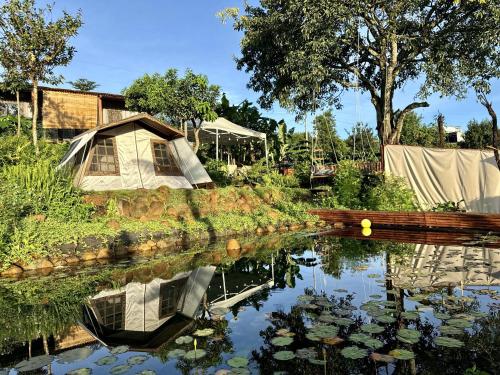 a garden with a house and a pond with lilies at Mầm Farmstay And Camping in Riong Thô (2)