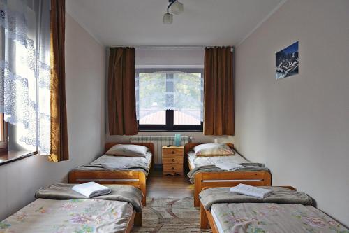 a room with three beds and a window at Pokoje Gościnne u Wioli in Jurgów