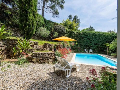 a swimming pool with a chair and an umbrella at Family Escape in Les Salelles in Chambonas