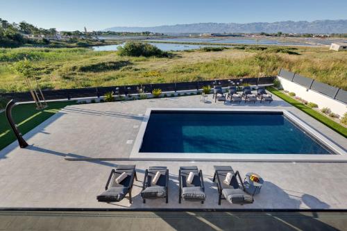 a pool with chaise lounge chairs and a swimming pool at Villa Dona ZadarVillas in Nin