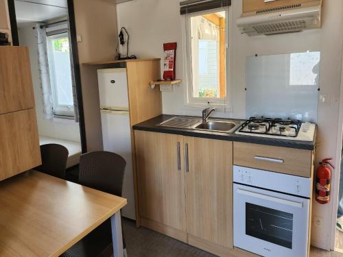 une petite cuisine avec un évier et une cuisinière dans l'établissement Mobile Home in Saint-Jean near Beach & Sauna, à Saint-Jean-de-Monts