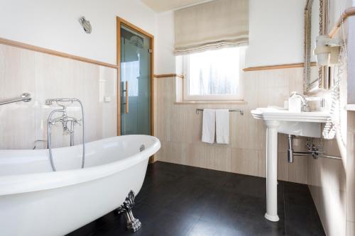 a bathroom with a white tub and a sink at Hotel MAYR in Castelrotto