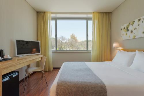 a hotel room with a bed and a desk and a television at HF Fenix Garden in Lisbon
