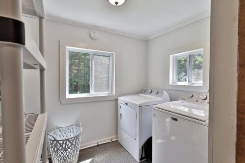 a laundry room with a washer and dryer and two windows at The Mendon Cottage - Charming Vermont Home Close to Pico, Ski Rental Deals! in Mendon