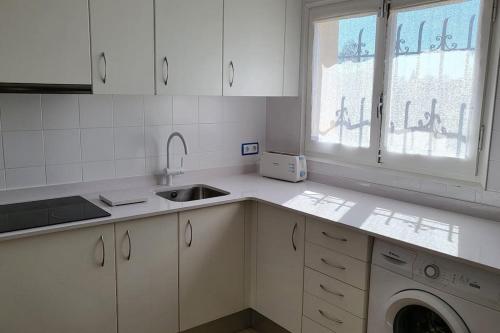 a kitchen with white cabinets and a sink and a window at Palmeres in Torroella de Montgrí