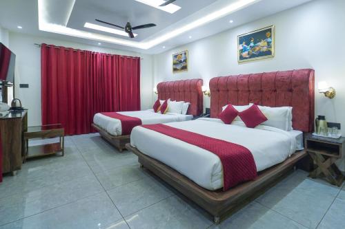 two beds in a hotel room with red curtains at Hotel The Vaishvik in Katra