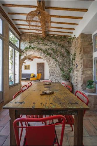 une salle à manger avec une table en bois et des chaises rouges dans l'établissement Maison d'exception au cœur de Goult, à Goult