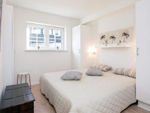 a white bedroom with a large bed with two pillows at 5 person holiday home on a holiday park in Bogense in Bogense