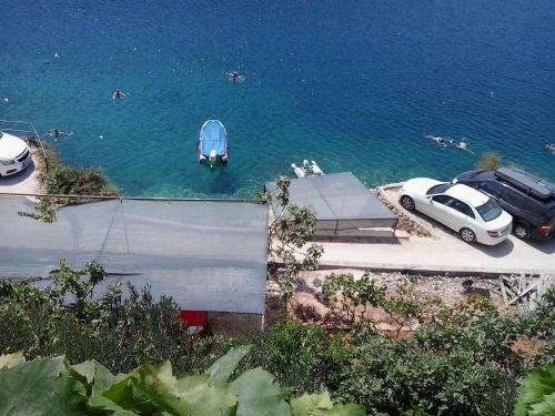a boat in the water with cars parked next to it at Apartments Ivan in Vinišće