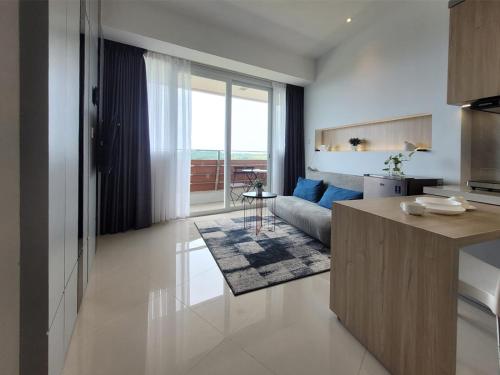 eine Küche und ein Wohnzimmer mit einer Couch und einem Tisch in der Unterkunft Apartment Nuvasa Bay Nongsa, Kalani 1BR 12th, Sea & Golf View in Telukmataikan