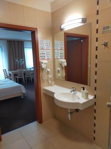 a bathroom with a sink and a mirror and a bed at Karpacz Residence 107A in Karpacz