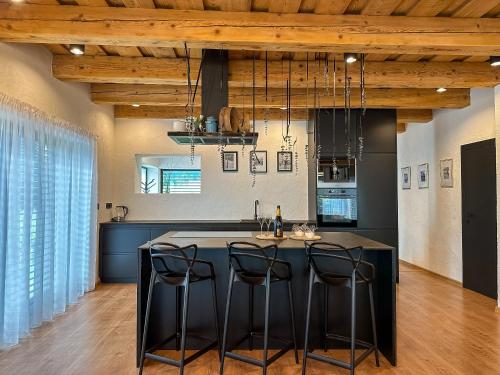 Una cocina con una isla negra con taburetes de bar. en Chalet Black Deer, en Mýto pod Ďumbierom