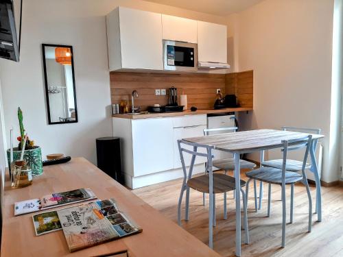 une cuisine avec une table et des chaises dans une pièce dans l'établissement Les Apparts de Marmande - Appart Cosy, centre de Marmande, à Marmande