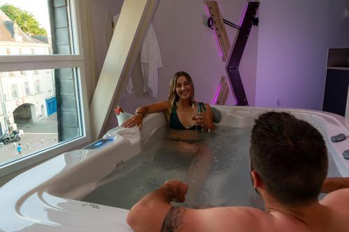 un homme et une femme dans une baignoire dans l'établissement LOVESENSE by LeSaumurTranquille, à Saumur