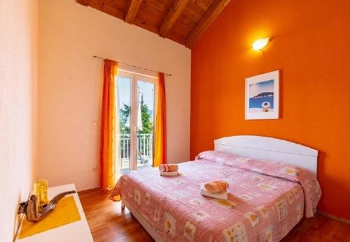a bedroom with a bed with orange walls and a window at Apartments Zeljko in Račišće