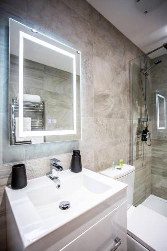 a bathroom with a white sink and a mirror at The Cove - Roker Sea Front - Vacant Nests in Monkwearmouth