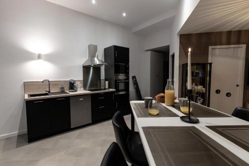 une cuisine avec des armoires noires et une table avec des chaises dans l'établissement LOVESENSE by LeSaumurTranquille, à Saumur