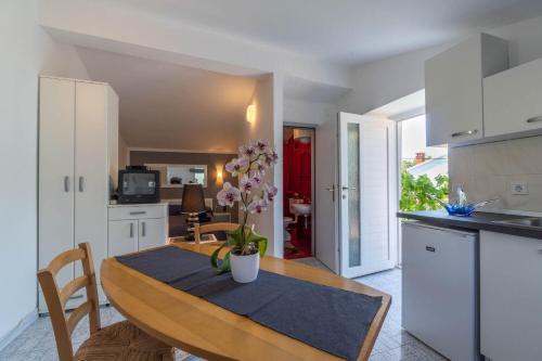 een keuken en eetkamer met een tafel met bloemen erop bij Apartments Perci in Krnica
