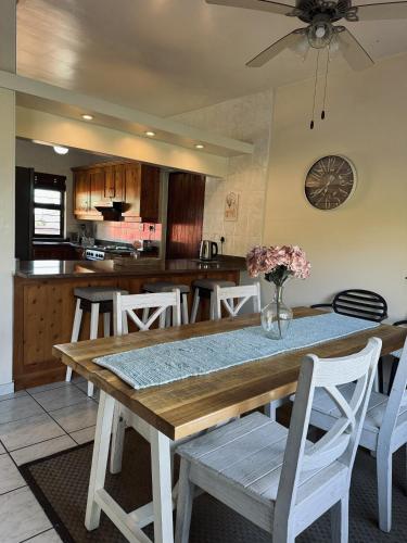Una cocina con una mesa de madera y sillas blancas. en Rockshore at Seaverge, en Port Edward