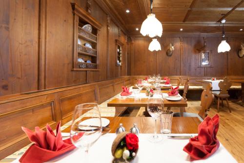 a restaurant with wooden walls and tables with red napkins at Sporthotel Wildstrubel in Lenk