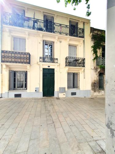 - un bâtiment blanc avec une porte verte et des balcons dans l'établissement Le Triompha Montpellier Proche Arc de Triomphe, à Montpellier
