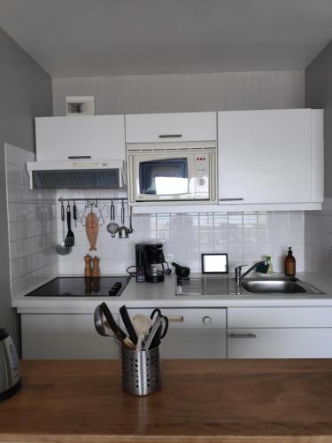 - une cuisine avec des placards blancs et des ustensiles de cuisine dans l'établissement Duplex 4 personnes - Face mer, à Bray-Dunes