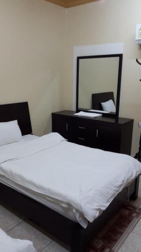 a bedroom with two beds and a dresser with a mirror at Bahget Eljouf Furnished Apartment in Sakakah