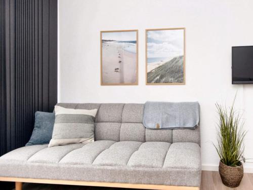 a living room with a couch and three pictures on the wall at Apartment in Holiday park- shared kitchen in Ulfborg