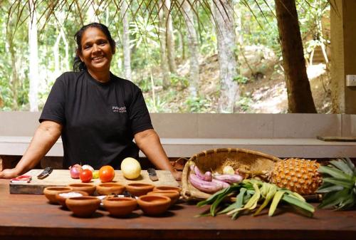 a man standing next to a table with fruits and vegetables at Polwaththa Eco Lodges in Digana