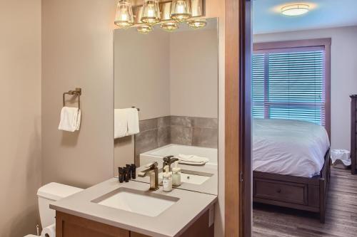 a bathroom with a sink and a bed and a mirror at Stonegate Resort Unit B105 in Big White