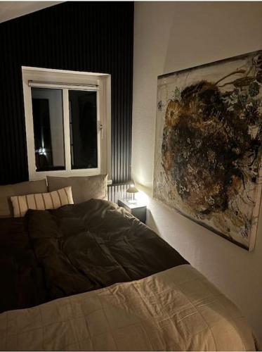 a bedroom with a bed and a painting on the wall at En SMUK og CHARMERENDE OASE meget tæt på centrum! in Holstebro