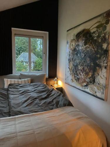 a bedroom with a bed and a painting on the wall at En SMUK og CHARMERENDE OASE meget tæt på centrum! in Holstebro