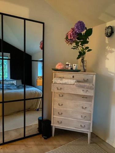 a bedroom with a dresser with a mirror and a bed at En SMUK og CHARMERENDE OASE meget tæt på centrum! in Holstebro