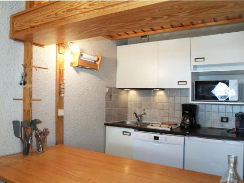 une cuisine avec des armoires blanches et un comptoir dans l'établissement Spacieux studio 6 pers avec balcon aux Orres 1650 - FR-1-322-560, aux Orres