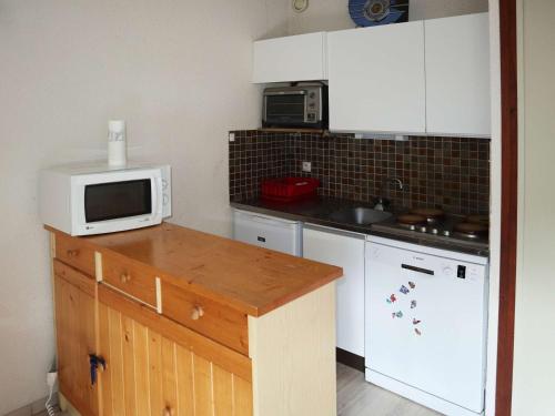 La cuisine est équipée de placards blancs et d'un four micro-ondes blanc. dans l'établissement Appartement Confort 6 Pers. Face Télésiège, Commerces & Animations - Les Orres 1650 - FR-1-322-592, aux Orres